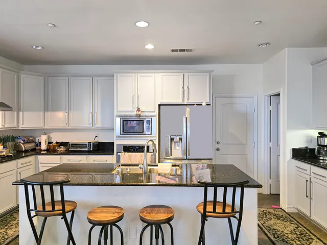 a kitchen with stainless steel appliances granite countertop a stove and a white cabinets