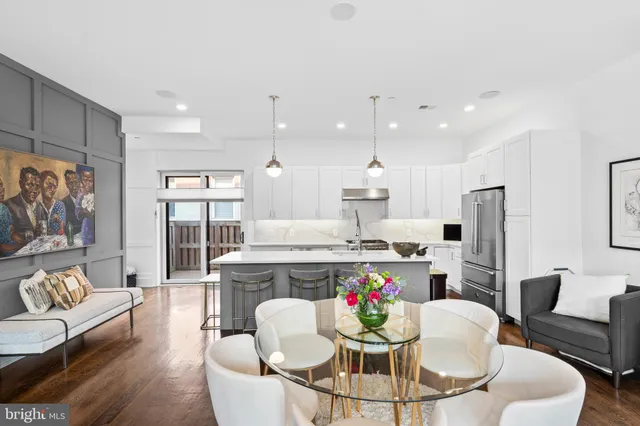 a living room with stainless steel appliances furniture a dining table and kitchen view