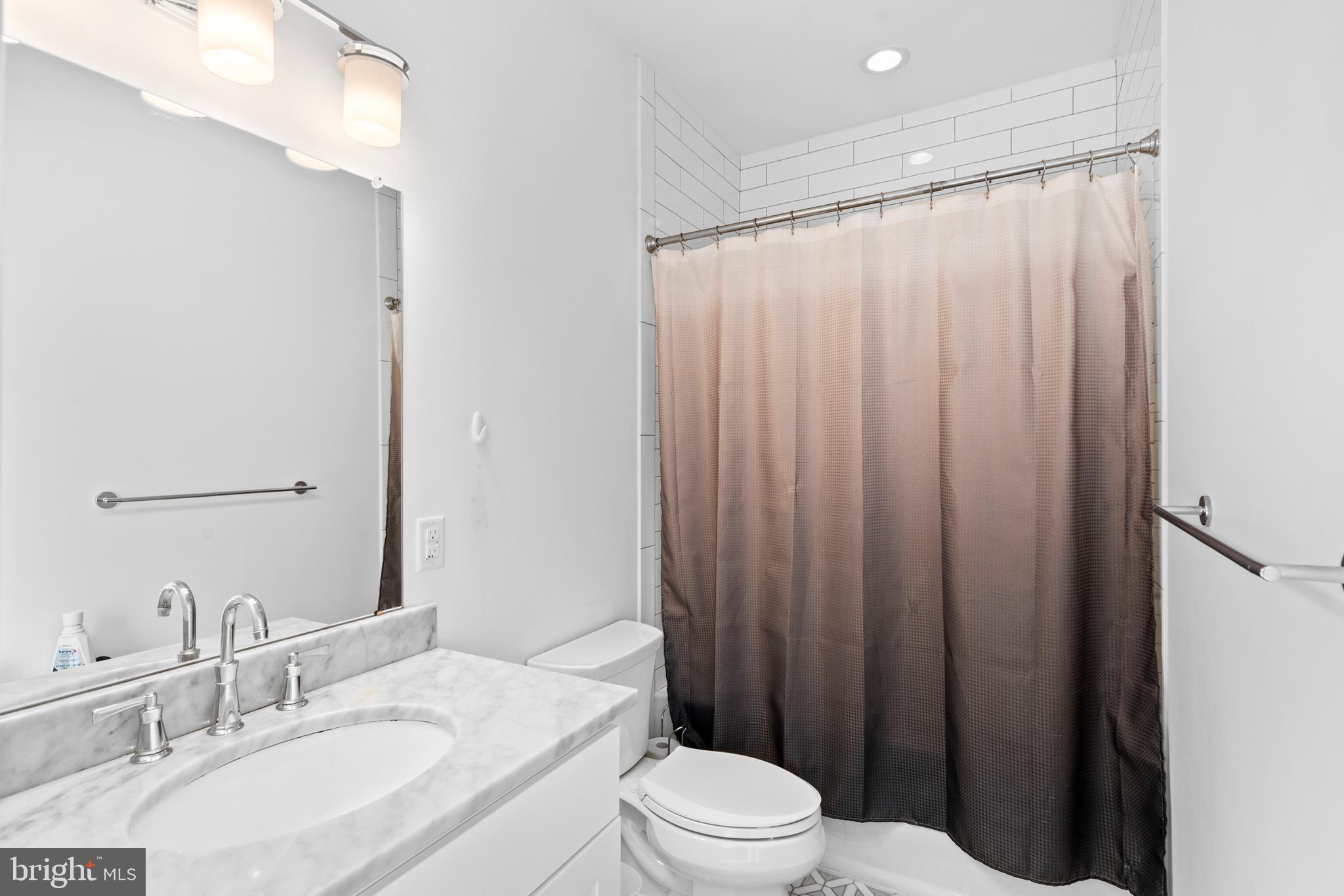 606 North 16th Street Philadelphia, PA 19130 - Photo 29 of 43 a bathroom with a sink a toilet a mirror and shower curtain
