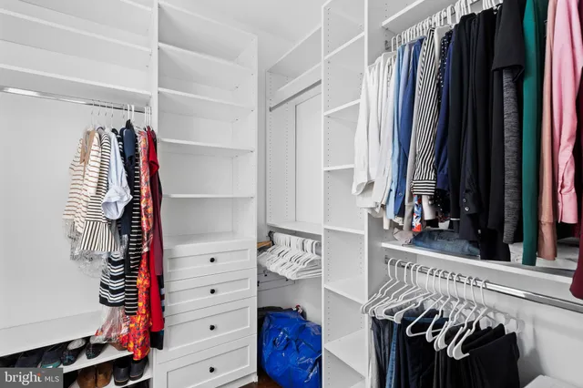 a view of walk in closet with clothes and shoes