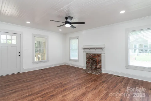a view of an empty room with a window and wooden floor
