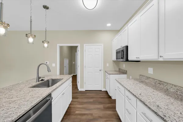 a kitchen with stainless steel appliances granite countertop a sink and dishwasher with white cabinets