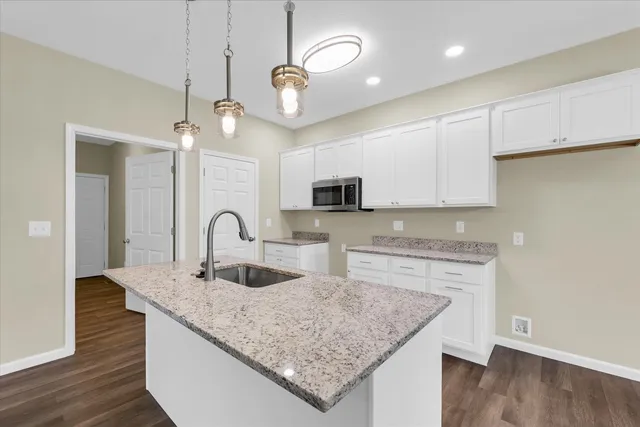 a kitchen with stainless steel appliances granite countertop a sink dishwasher and white cabinets with wooden floor