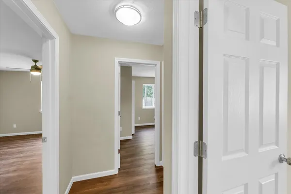 a view of an empty room with wooden floor and a window