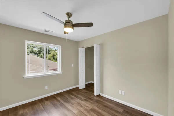 an empty room with wooden floor fan and windows