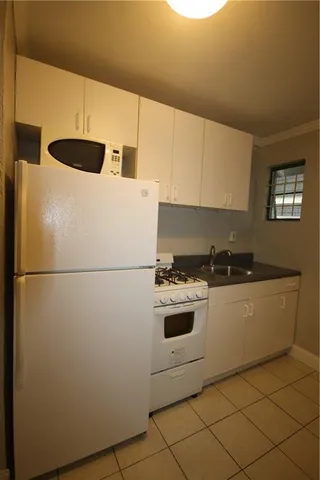 a view of a refrigerator in kitchen and an empty room