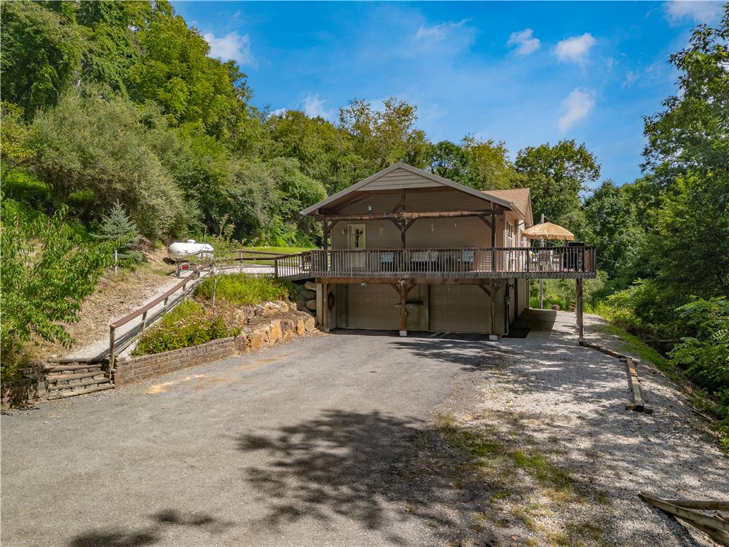 7353 Farrier Road Orefield, PA 18069 - Photo 60 of 74 An expansive upper-level deck sits above dual garage bays in this wooded hillside setting.
