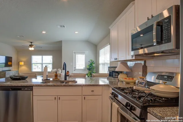 a kitchen with stainless steel appliances granite countertop a stove a sink and a microwave