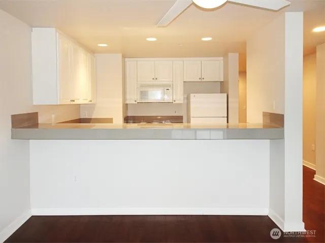 a view of kitchen with kitchen island a sink wooden floor and a counter top space