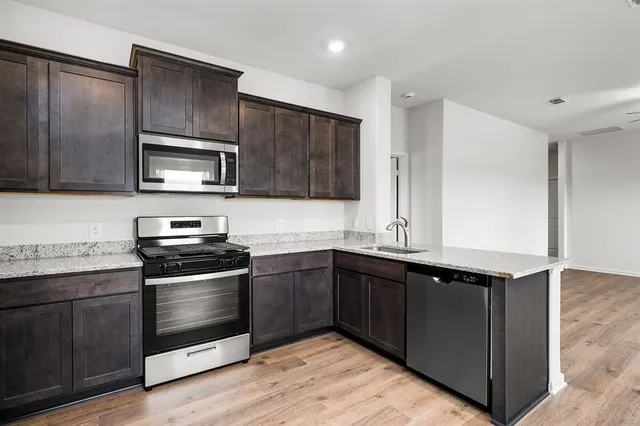 a kitchen with stainless steel appliances granite countertop a stove a sink and a microwave