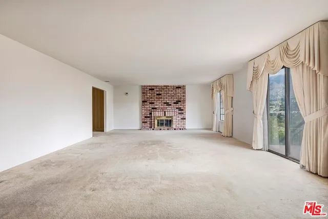 a view of an empty room with a fireplace and a window
