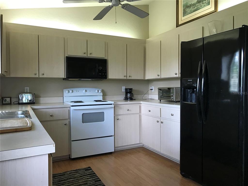 11879 Southwest 137th Loop Dunnellon, FL 34432 - Photo 24 of 37 a kitchen with a refrigerator stove and white cabinets