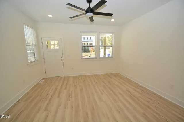a view of an empty room with a window and wooden floor