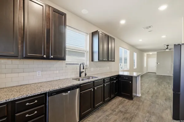a kitchen with granite countertop stainless steel appliances a sink stove and cabinets