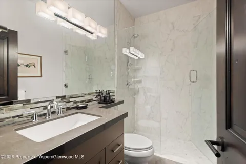 a bathroom with a granite countertop sink a toilet a mirror a bathtub and shower