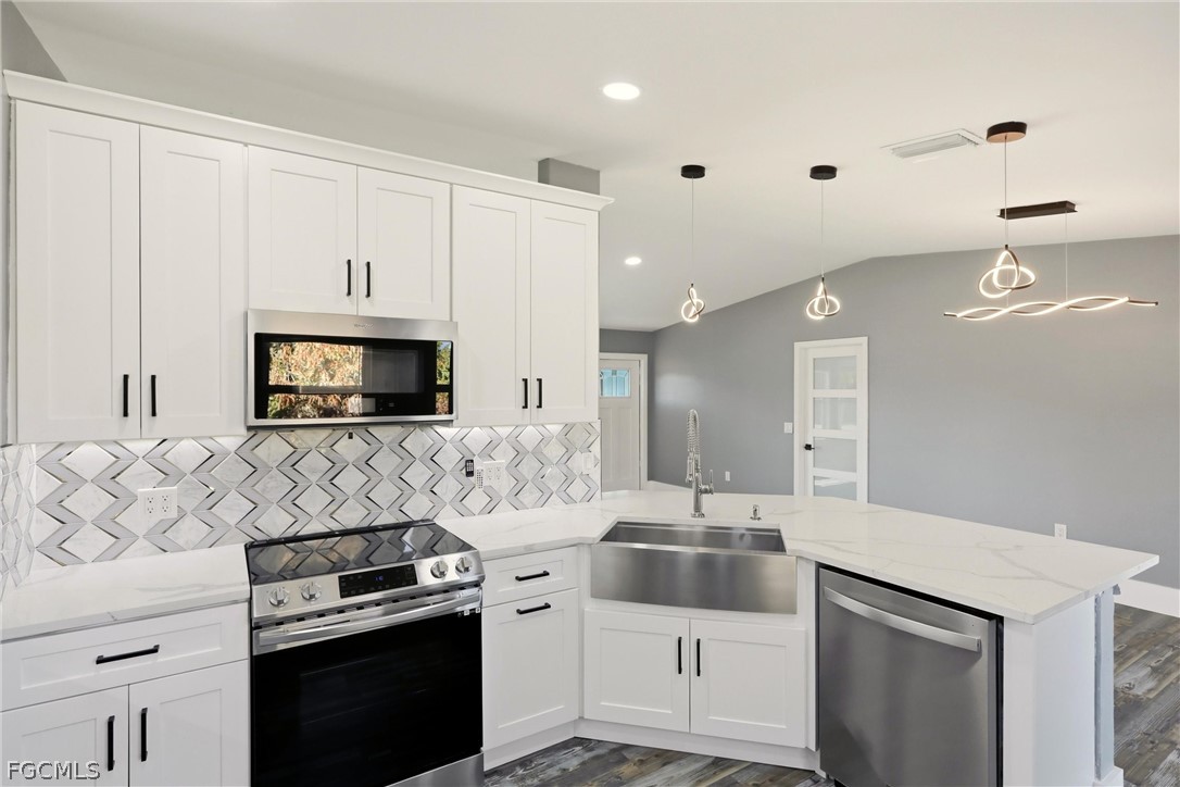 3404 2nd Street Southwest Lehigh Acres, FL 33976 - Photo 16 of 41 a kitchen with stainless steel appliances a stove microwave and sink