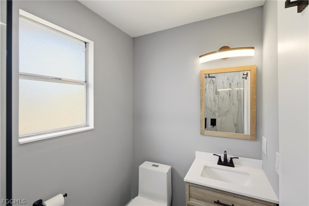 3404 2nd Street Southwest Lehigh Acres, FL 33976 - Photo 22 of 41 a bathroom with a sink a mirror and a toilet