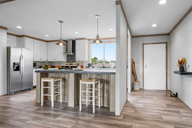 a kitchen with stainless steel appliances kitchen island granite countertop a refrigerator a stove and a sink