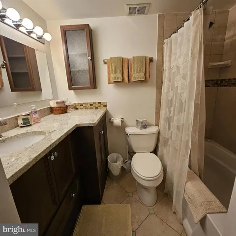 a bathroom with a granite countertop toilet sink and mirror