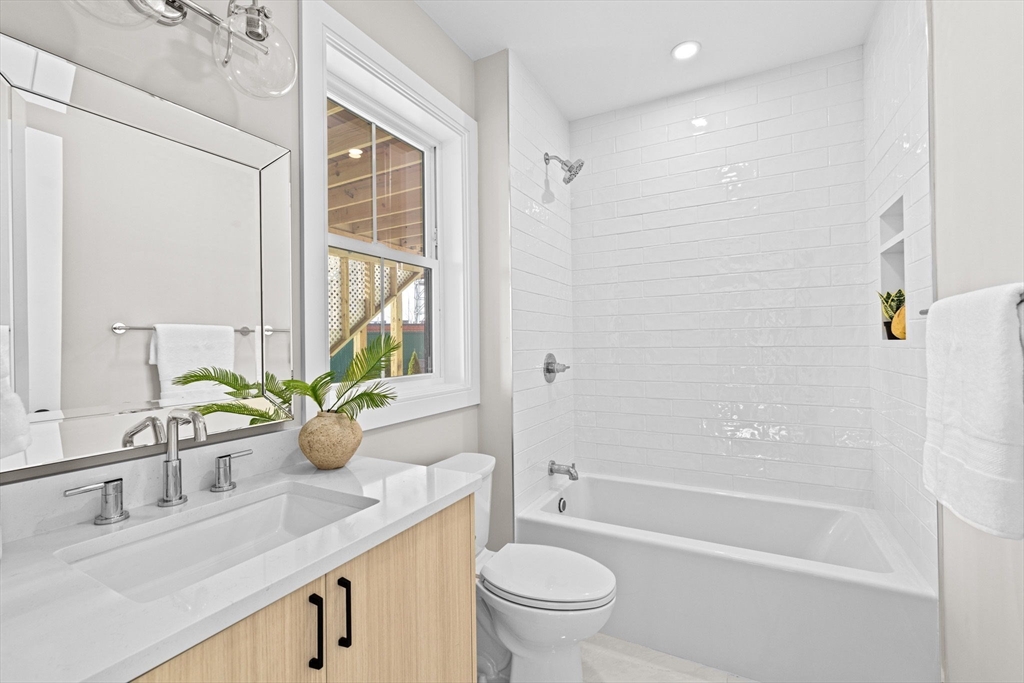 340 Baker Street, Unit 1 Boston, MA 02132 - Photo 30 of 41 a bathroom with a granite countertop sink a toilet a mirror a vanity a bathtub and shower