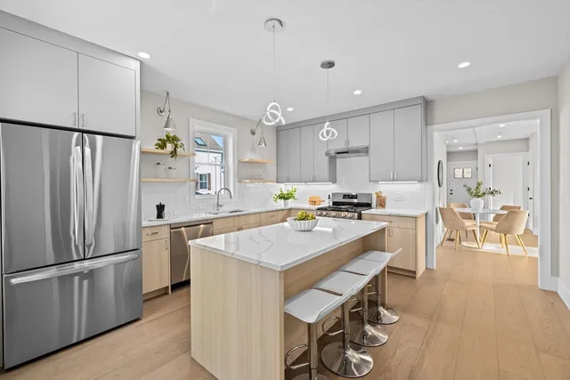 a kitchen with stainless steel appliances a refrigerator a stove a sink a dining table and chairs