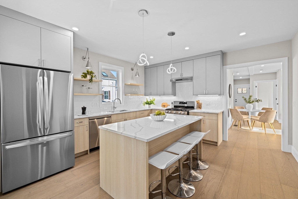 340 Baker Street, Unit 1 Boston, MA 02132 - Photo 3 of 41 a kitchen with stainless steel appliances a refrigerator a stove a sink a dining table and chairs