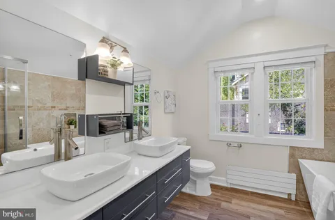 a bathroom with a granite countertop sink a toilet a mirror and shower
