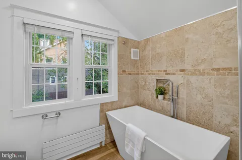 a bathroom with a tub a sink and a window