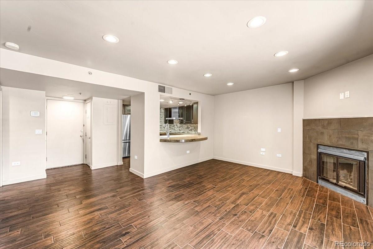 350 Detroit Street, Unit 103 Denver, CO 80206 - Photo 2 of 15 an empty room with wooden floor a fireplace and kitchen view