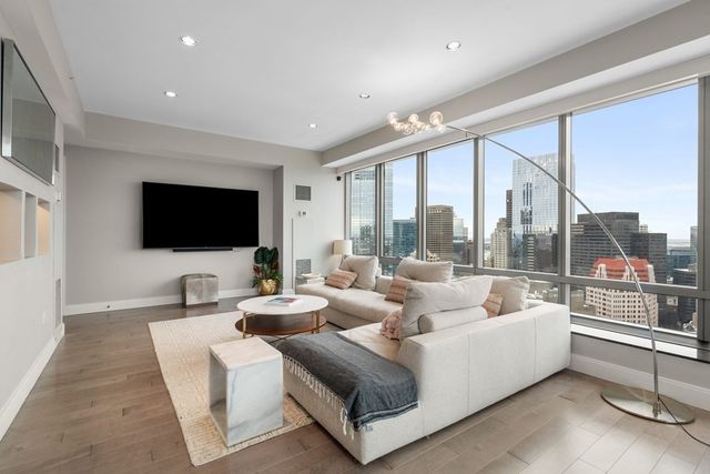 a living room with couch a flat screen tv and a large window