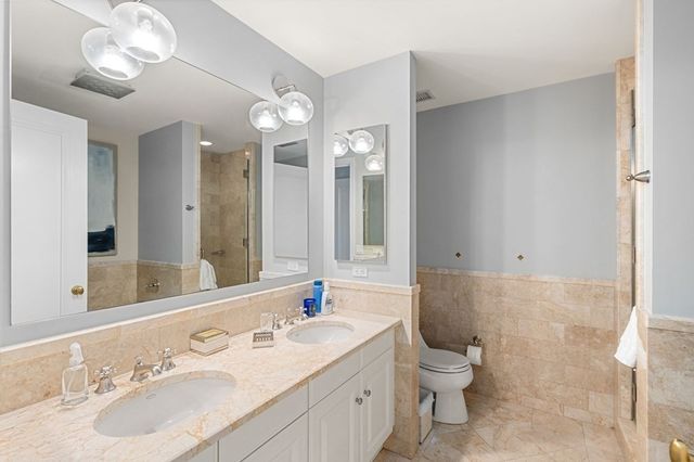 a bathroom with a double vanity sink mirror and toilet