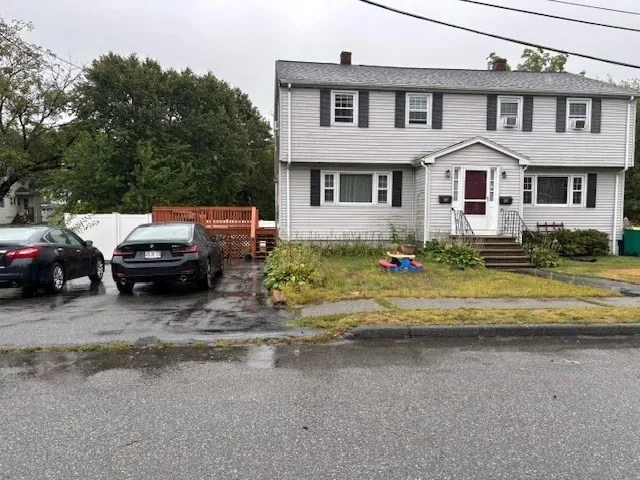 a view of a white house next to a yard with big trees