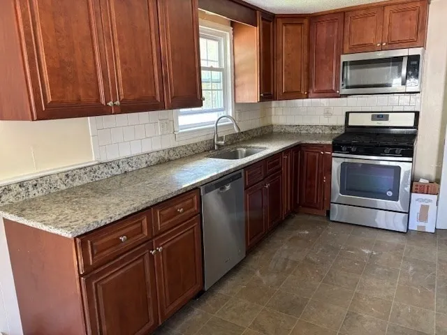 a kitchen with stainless steel appliances granite countertop a sink stove and microwave