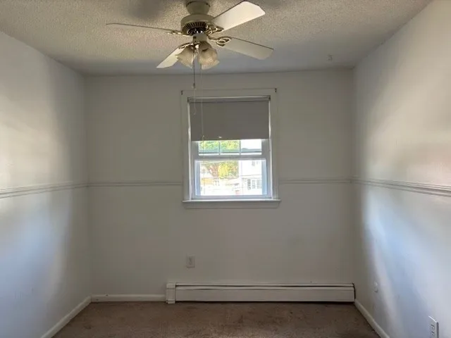 an empty room with a window and a fan
