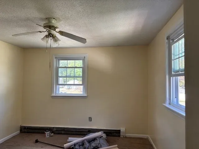 an empty room with windows and fan