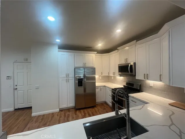 a kitchen with kitchen island a counter top space a sink stainless steel appliances and cabinets