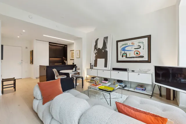 a living room with furniture a flat screen tv and kitchen view