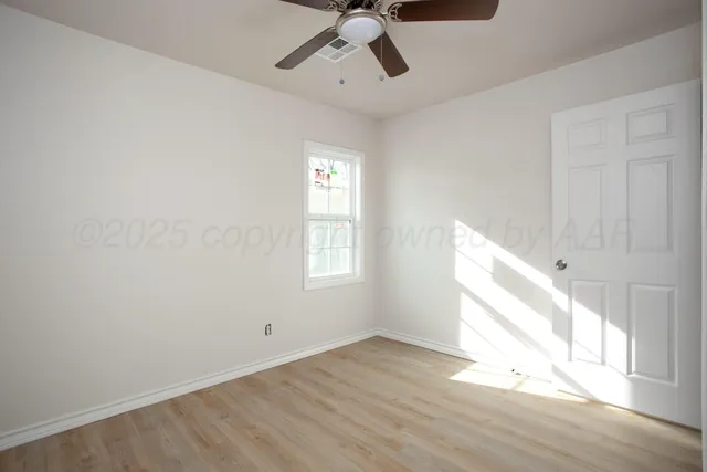 a view of empty room with wooden floor and fan