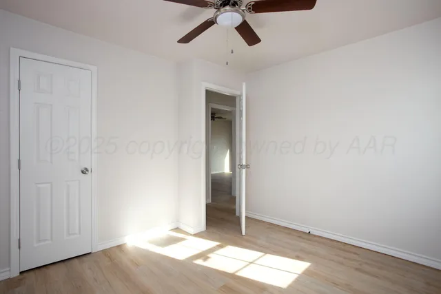a view of empty room with wooden floor and ceiling fan