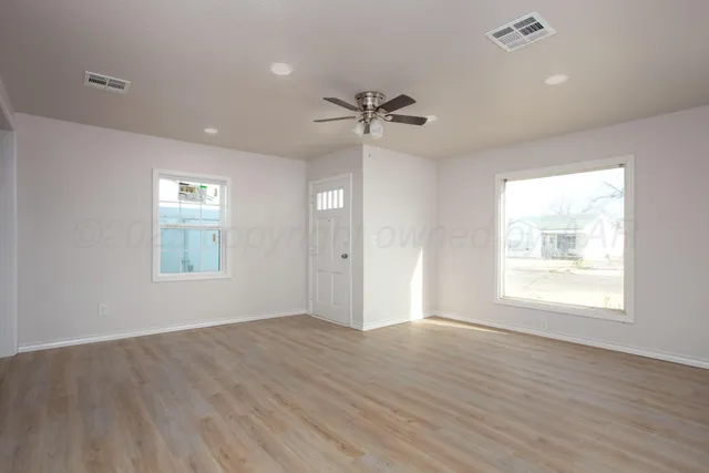 a view of an empty room with a window and wooden floor