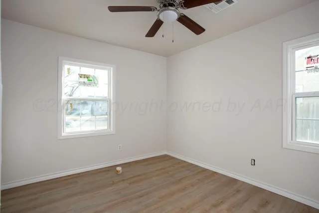 a view of an empty room with a window and wooden floor