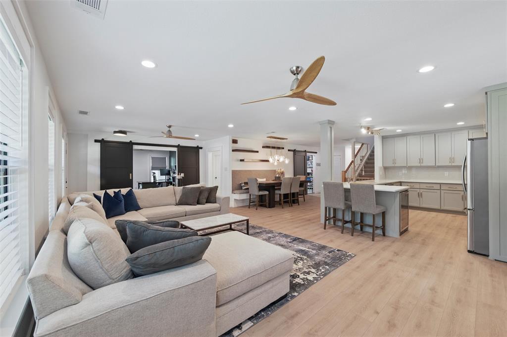 Living area with ceiling fan, a barn door, recessed lighting, light wood finished floors, and stairs