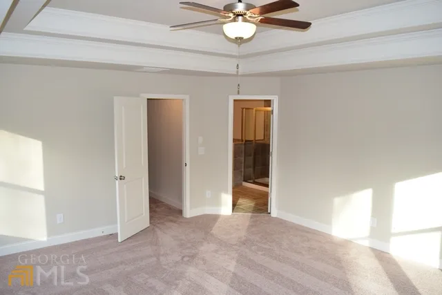 an empty room with a chandelier fan and windows