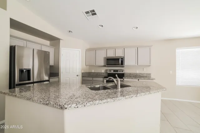 a kitchen with stainless steel appliances granite countertop a sink a stove and a refrigerator