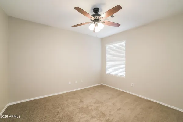an empty room with a chandelier fan and windows