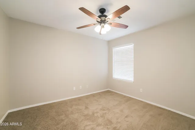 an empty room with a chandelier fan and windows
