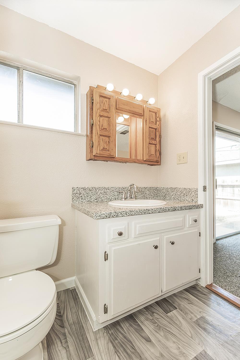 1375 South Cyrier Avenue Reedley, CA 93654 - Photo 17 of 34 a bathroom with a granite countertop toilet sink and mirror