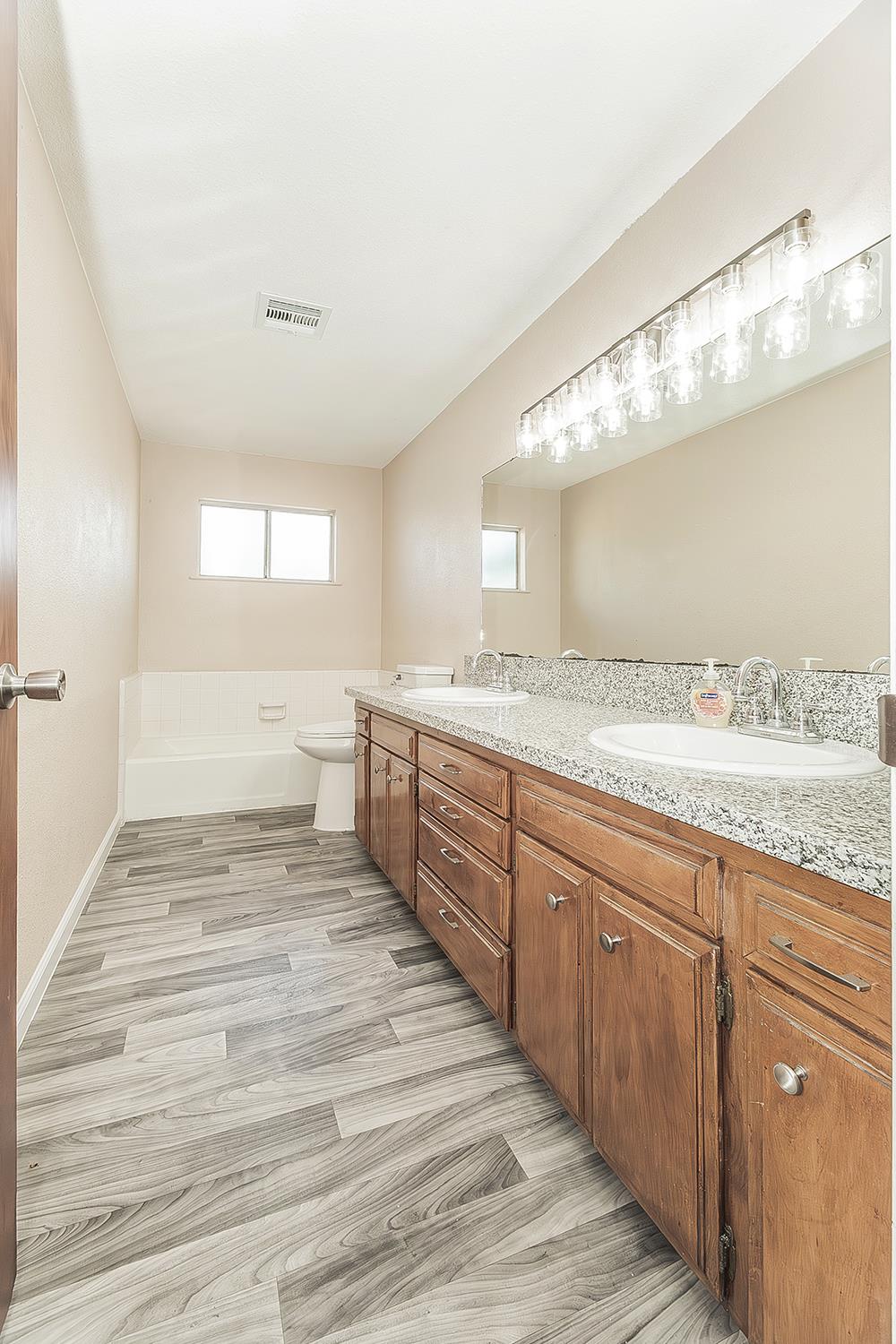 1375 South Cyrier Avenue Reedley, CA 93654 - Photo 21 of 34 a spacious bathroom with a granite countertop sink mirror and a bathtub