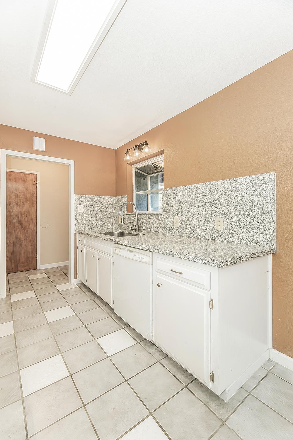 1375 South Cyrier Avenue Reedley, CA 93654 - Photo 10 of 34 a kitchen with granite countertop a sink and white cabinets
