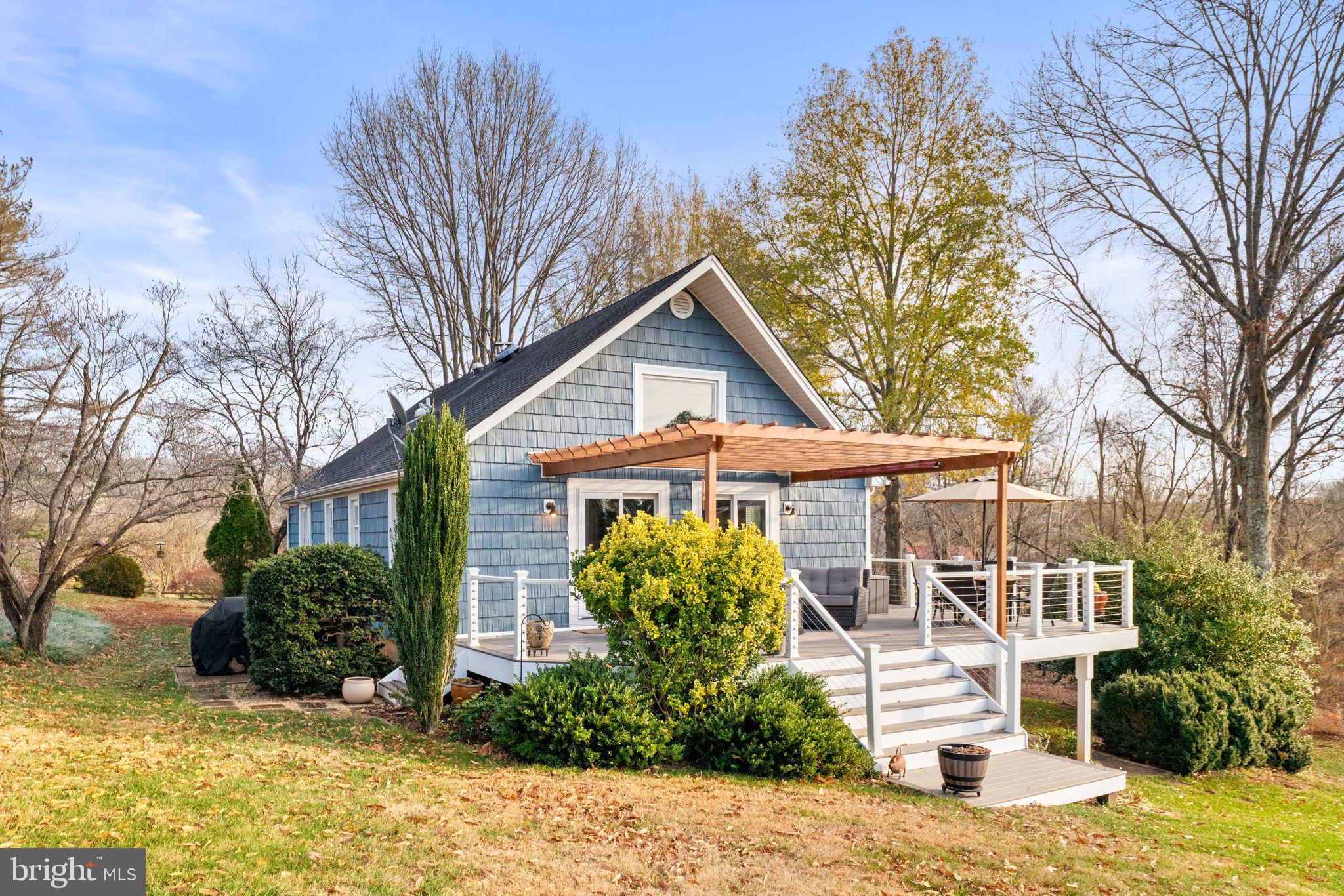 9666 Springs Road Warrenton, VA 20186 - Photo 61 of 77 a view of a white house with a large tree and plants
